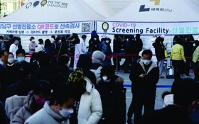人們在韓國首爾江南區一處新冠檢測點排隊等待核酸採樣。