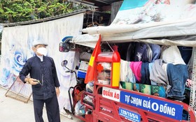 阮文四在堆滿舊衣服的車子旁邊。
