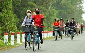 遊客在平政縣黎明春鄉體驗騎自行車遊覽賞景行程。