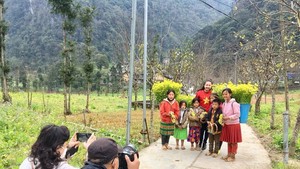 HCMC tourists are taking pictures of children in Lung Cam Cultural Tourism Village in Ha Giang Province. (Photo: SGGP) 