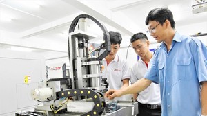 Lam Duc Sinh, a teacher in HCMC College of Economy – Technology, is guiding his students to operate the mini CNC machine model in their practice session 