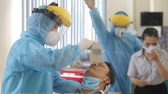 Các y bác sỹ Trung tâm y tế Quận 7 thực hiện xét nghiệm sàng lọc COVID-19 ngẫu nhiên cho công nhân tại Công ty TNHH Kim may Organ Việt Nam. (Ảnh: Thanh Vũ/TTXVN)