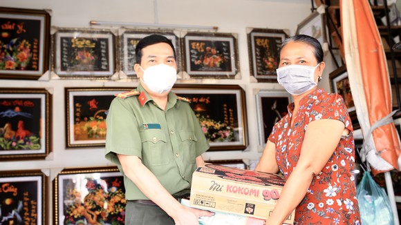 Đại tá Nguyễn Sỹ Quang, Phó Giám đốc Công an TPHCM trao quà cho gia đình chị Thuỷ. Ảnh: DŨNG PHƯƠNG
