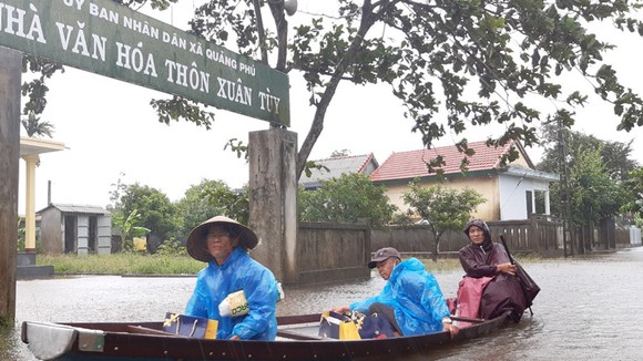 Người dân huyện Quảng Điền, tỉnh Thừa Thiên - Huế di chuyển trên đường ngập lụt, chiều 17-10. Ảnh: VĂN THẮNG