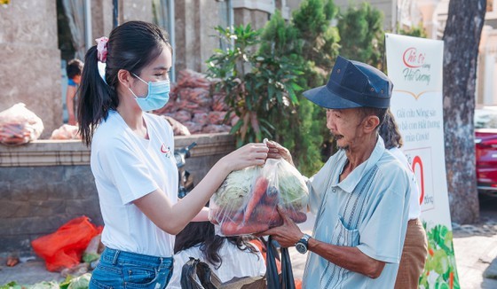 The first runner-up of Miss Vietnam 2020, Pham Ngoc Phuong Anh presents agricultural products to a person. (Photo: SGGP)