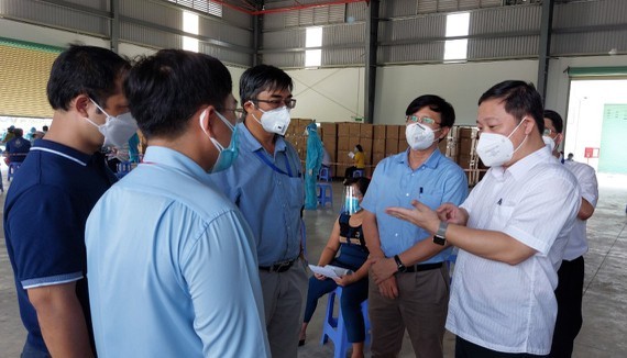 HCMC People's Committee Vice Chairman Duong Anh Duc (R) inspects the Covid-19 vaccination at the Nam Anh Production and Trade Company in the Tan Tao Industrial Zone in Binh Tan District. (Photo: SGGP)