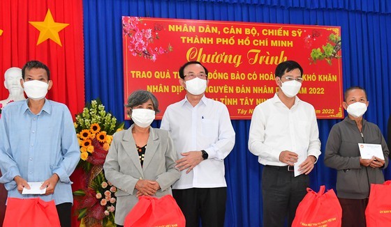 Secretary of the HCMC Party Committee Nguyen Van Nen (3rd, L), Secretary of the Party Committee cum Chairman of the People’s Council of Tay Ninh Province Nguyen Thanh Tam (2nd, R) offer Tet gifts to disadvantaged people.