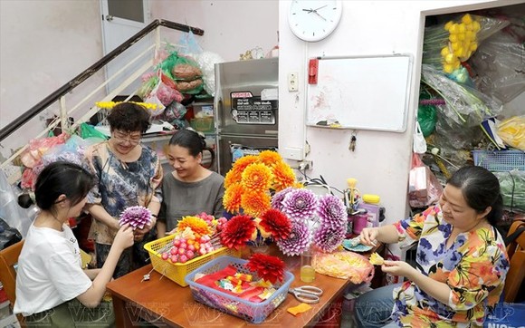 梅幸藝人向年輕人指導製作絹花。