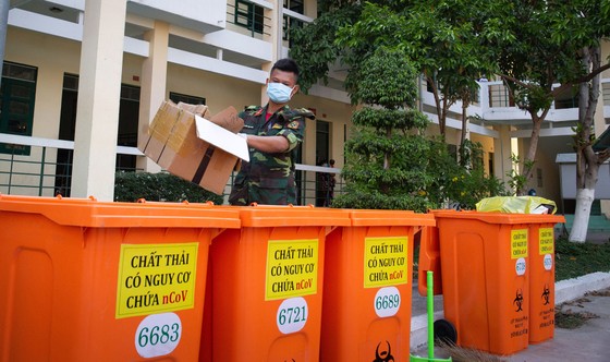 Các chiến sĩ Trường Quân sự Quân khu 7 (quận 12, TPHCM) cẩn thận thu gom, phân loại rác để vào các thùng màu cam chuyên dụng chứa rác độc hại tại khu cách ly. Ảnh: HOÀNG HÙNG