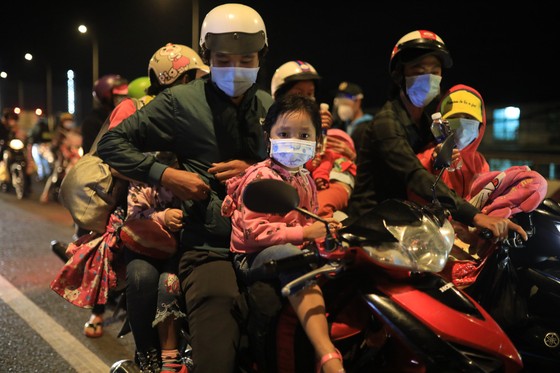 Người dân chở theo con nhỏ, hành lý... đi xe máy từ tỉnh Bình Dương qua TPHCM để về các tỉnh miền Tây. Ảnh: CHÍ THẠCH 