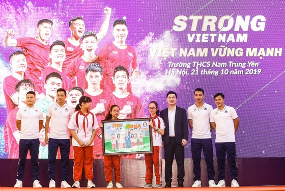 Các cầu thủ CLB bóng đá Hà Nội và Trưởng Ban tổ chức chương trình “Strong Vietnam” Đỗ Vinh Quang nhận quà là bức tranh từ các em học sinh THCS Nam Trung Yên