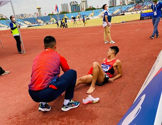Nguyễn Tiến Trọng nhanh chóng giúp người đồng đội Trần Văn Đảng cởi giầy, sơ cứu ngay khi bị đau sau khi kết thúc thi đấu 800m. Ảnh: MINH CHIẾN