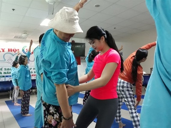 Dang Thi Quynh Nhu (center) adjusts body position for a cancer patient in her free yoga therapy class at the Da Nang City General Hospital. (Photo thanhnien.vn)