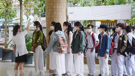 Students of Phan Chau Trinh High School in Da Nang City are standing in line to have their temperature checked. (Photo: VNA)