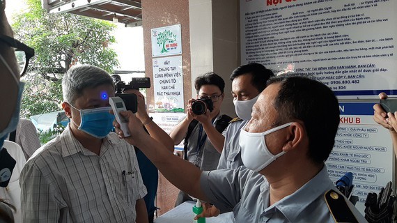 A medical worker measures temperature ofDeputy Health Minister Nguyen Truong Son (Photo: SGGP)