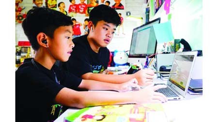 Third-grader Nguyen Huynh Thong is getting used to e-learning with the help of his brother, a seventh grader. (Photo: SGGP)