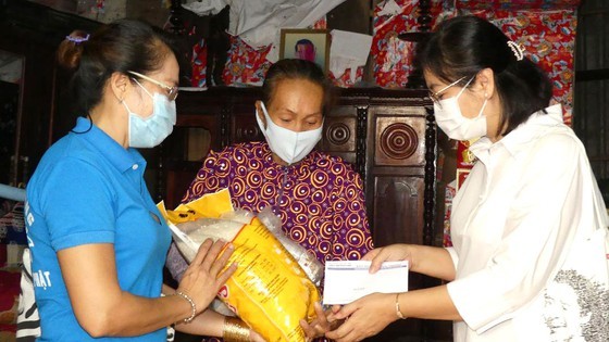 Deputy Editor-in-chief Ly Viet Trung (1st, R) presents gifts to poor laborers (Photo: SGGP)