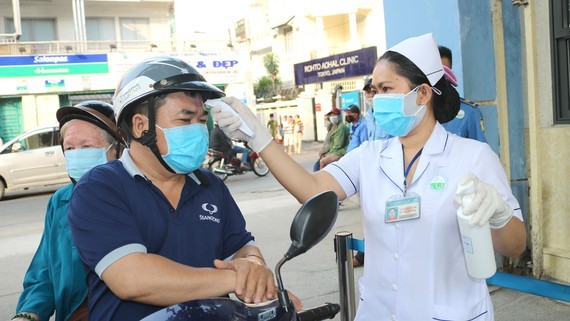 Relatives of patients are measured temperature before entering a hospital in HCMC (Photo: SGGP)