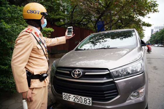 The police officer takes photos as an evidence of an illegally parking car (Photo: SGGP)