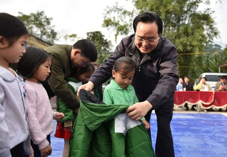 Minister Phung Xuan Nha is delivering warm clothes to poor children. (Photo: SGGP)