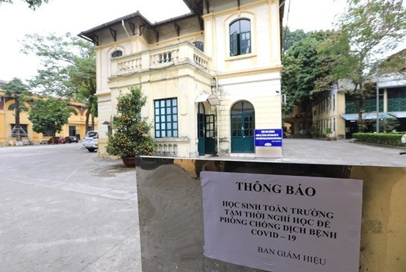 On the right is a notice from Phan Dinh Phung high school in Hanoi, which says all students temporarily skip going to the school for COVID-19 prevention and control (Photo: VNA)