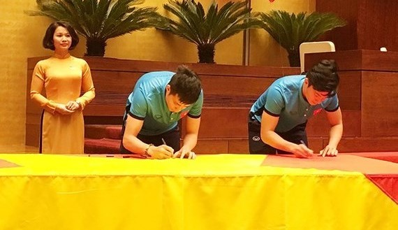 Vietnamese U23 footballers respectively sign names on national flag 