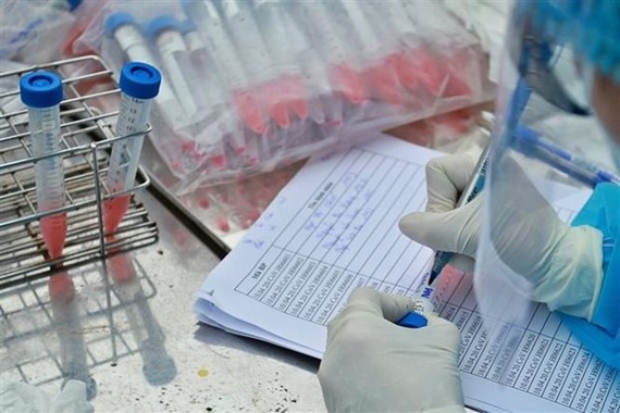 A medical worker of the Hanoi Centre for Disease Prevention and Control (CDC) takes samples from people for testing (Source: VNA)
