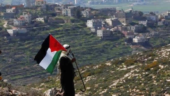 Một người đàn ông Palestine vẫy cờ Palestine trong cuộc biểu tình phản đối các khu định cư của Israel tại thành phố Nablus, Bờ Tây, hôm 26-2-2021. Ảnh: EPA