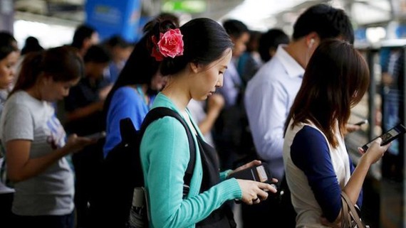 Sử dụng điện thoại di động tại một ga xe lửa ở Bangkok, Thái Lan. Ảnh: REUTERS