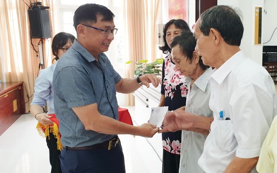 郡越南祖國陣線委員會副主席陳南德向高齡長者贈送禮物。