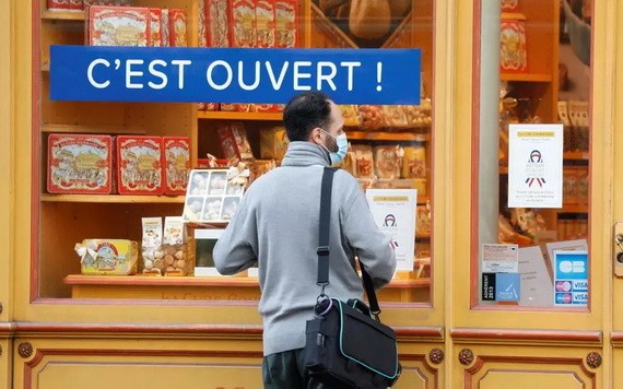 一名男子在巴黎的一家點心店前。櫥窗貼著藍幅寫道“開店營業”。（圖源：路透社）