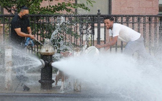 當地時間2020年7月27日，兩名青年在紐約布魯克林街道上噴水的消防栓前嬉水消暑。（圖源：Getty Images）