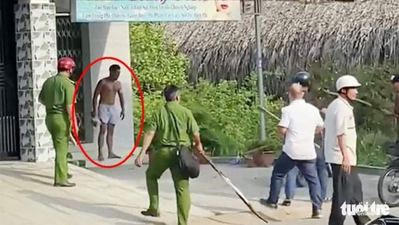 吳永貴（紅圈示）手持椰子刀襲擊咖啡店後站在外頭“迎戰”警方。（圖源：淮商）