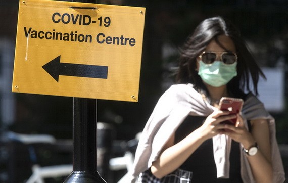 7月16日，行人走過英國倫敦街頭一個疫苗接種點的標誌牌。（圖源：新華社）