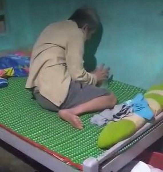 視頻畫面中顯示一位瘦小的父親坐在床上一角邊喝奶茶邊哭泣。