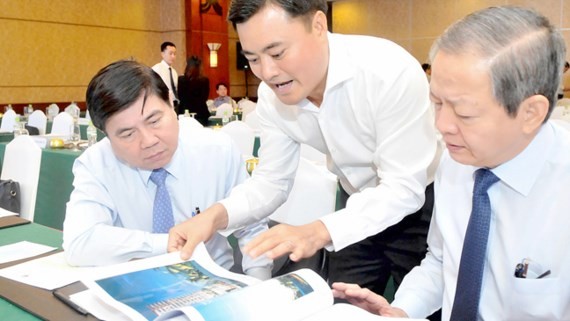 Chairman of the HCMC People’s Committee Nguyen Thanh Phong (L) and deputy Le Van Khoa (R) see an construction work sketch at the conference on June 14 (Photo: SGGP)