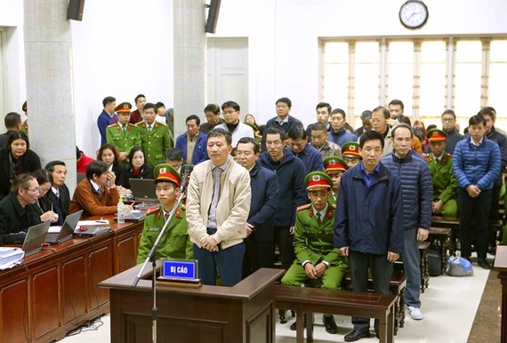 Trinh Xuan Thanh (standing in white jacket), and accomplices listen to the prosecutor’s arraignment. (Photo: VNA/VNS)