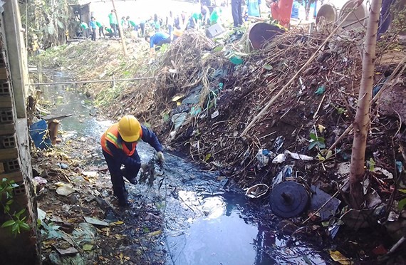 A worker collects garbage at a canal in HCMC (Photo: SGGP)