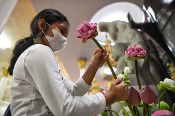 A young student is placing flowers at an altar in a Buddhist pagoda in Phnom Penh. (Photo: AFP)
