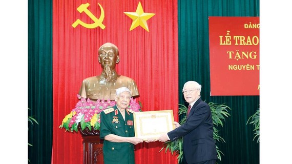 Tổng Bí thư, Chủ tịch nước Nguyễn Phú Trọng, Bí thư Quân ủy Trung ương trao Huy hiệu 70 năm tuổi Đảng tặng đồng chí Lê Khả Phiêu.  Ảnh: TTXVN