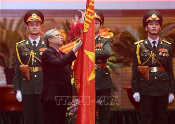 Đồng chí Trần Quốc Vượng, Thường trực Ban Bí thư gắn Huân chương Bảo vệ Tổ quốc hạng Nhất lên lá cờ truyền thống của Tổng cục Chính trị QĐND Việt Nam. Ảnh: TTXVN