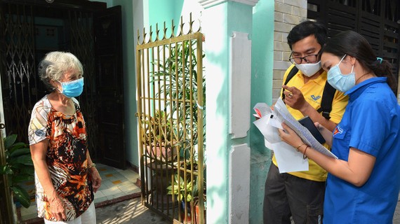 Bưu tá và chuyên viên UBND phường Tân Định (quận 1, TPHCM)  tới nhà chi trả chế độ ưu đãi người có công với cách mạng. Ảnh: VIỆT DŨNG