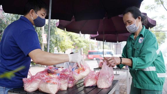 Người dân hoàn cảnh khó khăn đến nhận thực phẩm tại một điểm phát hàng từ thiện ở Hà Nội.  Ảnh: ĐỖ TRUNG