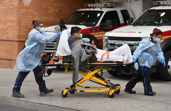 Nhân viên y tế chuyển bệnh nhân COVID-19 tới bệnh viện ở New York, Mỹ. Ảnh: AFP/ TTXVN