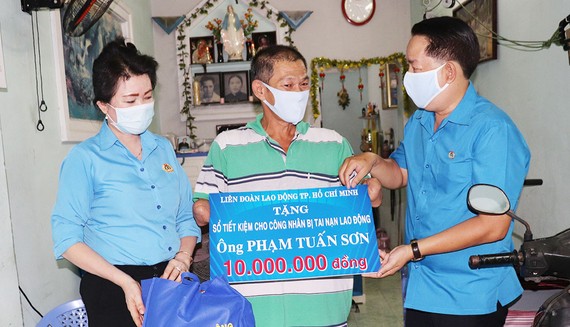 Đồng chí Kiều Ngọc Vũ, Phó Chủ tịch LĐLĐ TPHCM  (bên phải) trao tặng công nhân bị tai nạn lao động sổ tiết kiệm