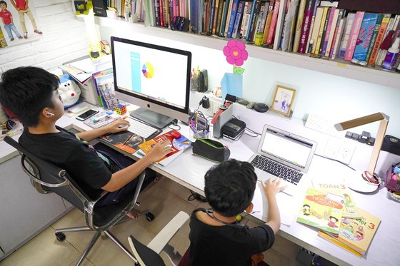 Hai em Nguyễn Huỳnh Bách (lớp 7 Trường THCS Đinh Thiện Lý) và Nguyễn Huỳnh Thông (lớp 3 Trường Tiểu học Võ Thị Sáu) học trực tuyến tại nhà. Ảnh: THANH TÙNG
