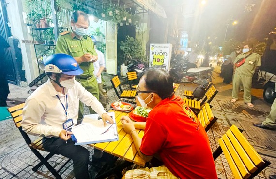 Đoàn kiểm tra phường 3 (quận Gò Vấp) lập biên bản một chủ quán  bán rượu bia cho thực khách vào đêm 2-11. Ảnh: VĂN MINH