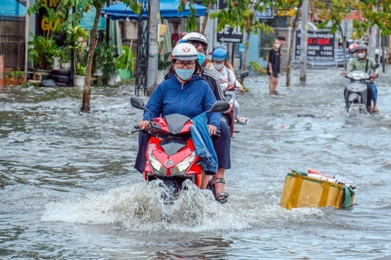 Nước ngập sâu trên tuyến đường ven hồ Búng Xáng khiến việc đi lại của người dân gặp khó khăn. Ảnh: TTXVN