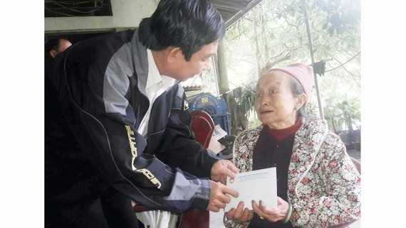Ông Đỗ Trung Tính trao tiền hỗ trợ  bà Nguyễn Thị Hường (ở tỉnh Hòa Bình,  có người thân bị lũ cuốn trôi)