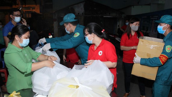 Các chiến sĩ dân phòng hỗ trợ tiếp tế cho bà con  đang cách ly tại khu Bình Tiên - Phạm Phú Thứ, quận 6. Ảnh: HOÀNG HÙNG
